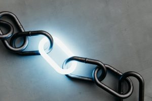 A single illuminated link shining in a dark metal chain on a concrete background, a symbol of power and connection.3d rendering