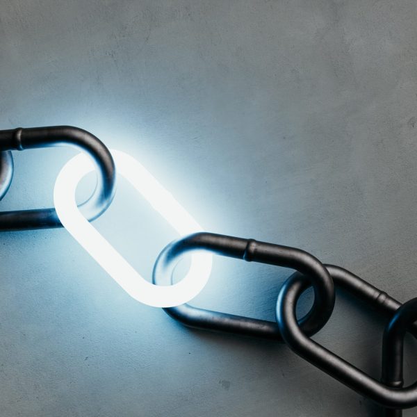 A single illuminated link shining in a dark metal chain on a concrete background, a symbol of power and connection.3d rendering